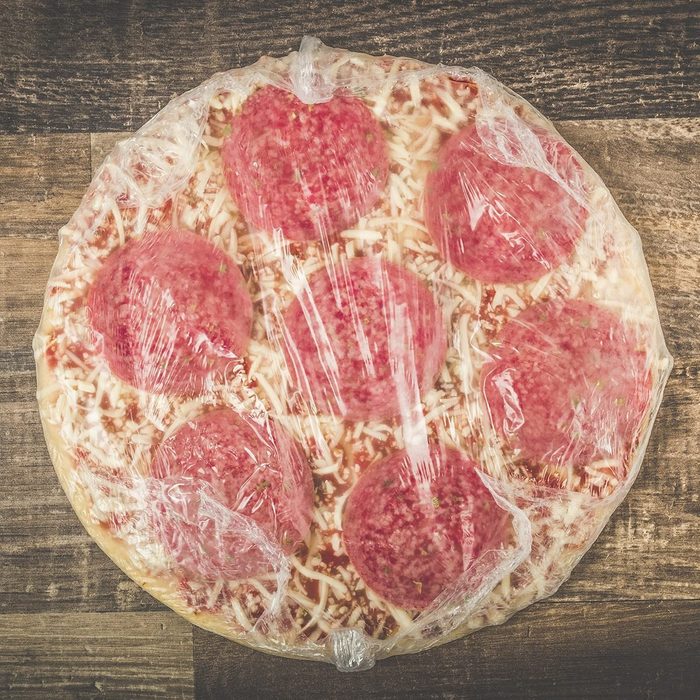Raw Frozen Pizza with Pepporoni on wood background