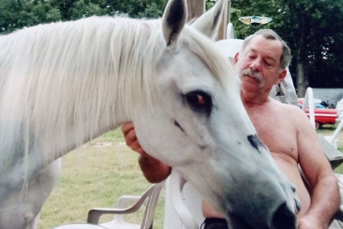 white horse being pet by a seated man