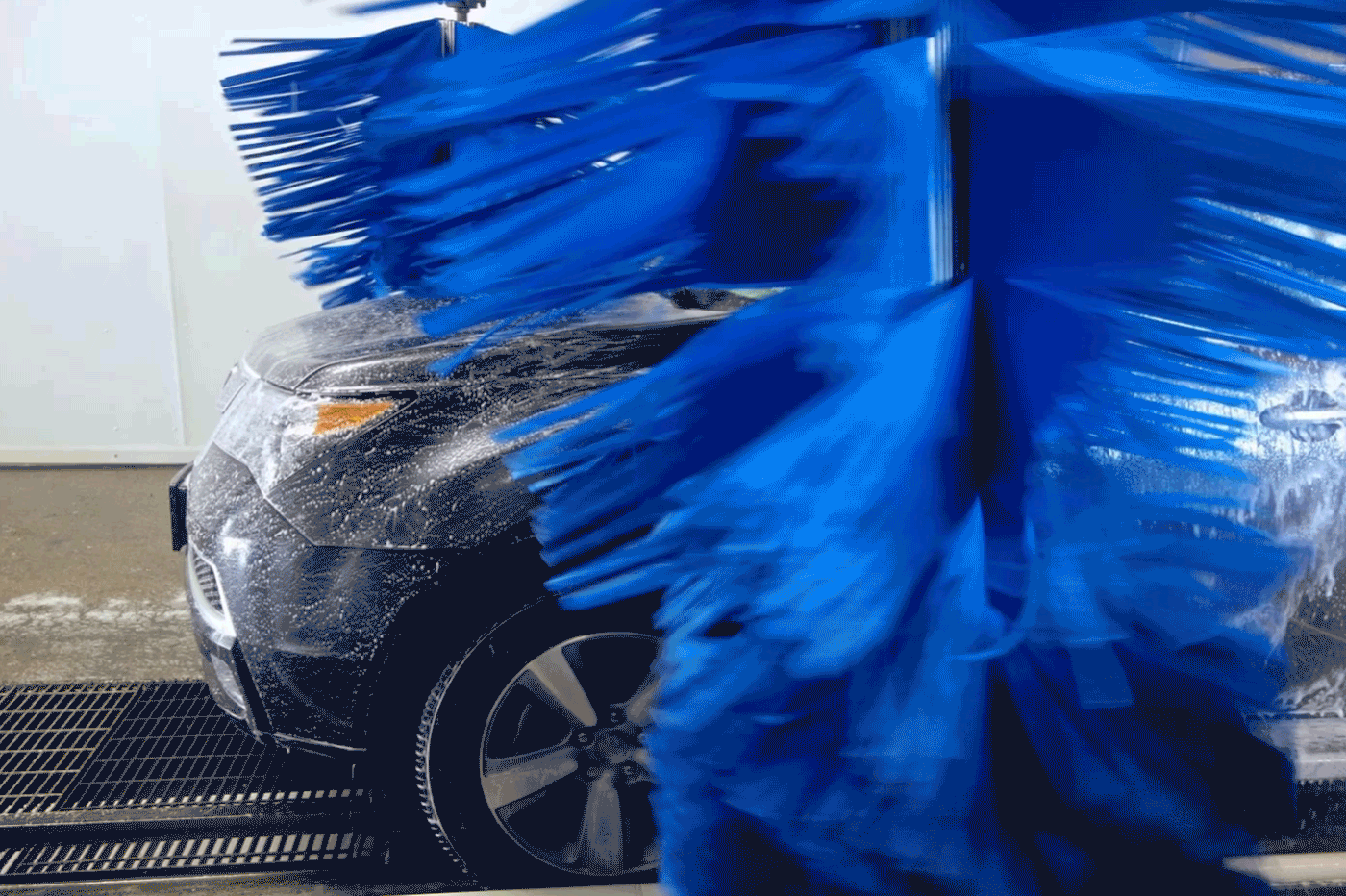 a dark car in a car wash with caution symbols popping up over the image