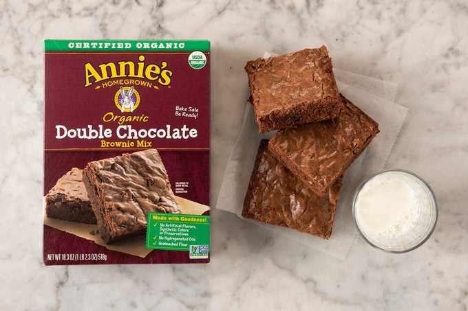 Annie’s Organic Double Chocolate Brownie Mix in package on marble with pieces and milk