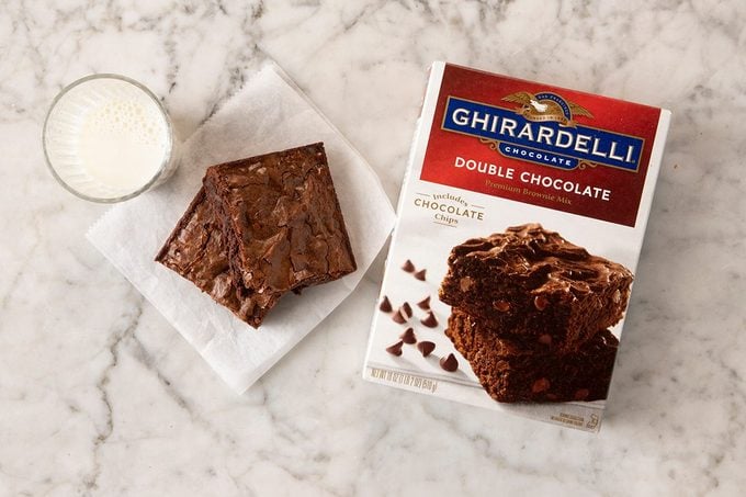 Ghiradelli Double Chocolate Brownie Mix in package on marble with pieces and milk