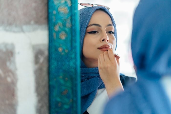 Young muslim woman applying make up