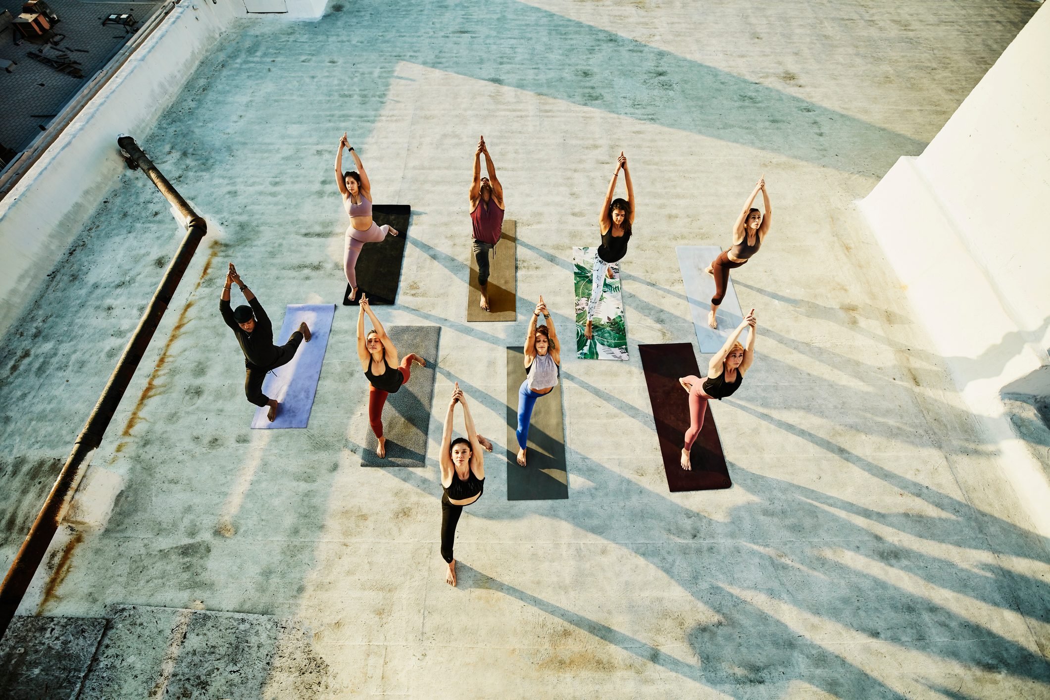 Overhead view of yoga class in warrior pose while practicing on rooftop