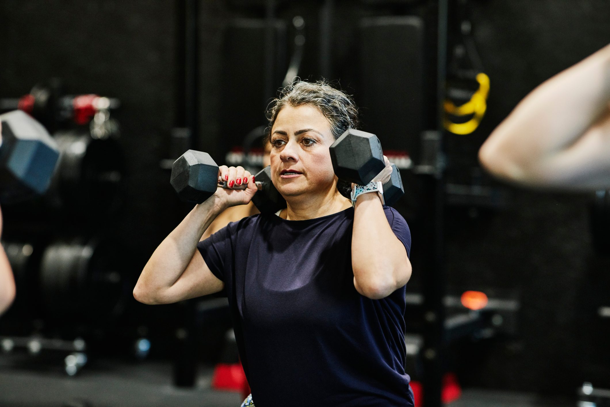 Woman doing dumbbell squats during fitness class in gym