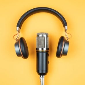 directly above view of headphones and podcast microphone on orange background