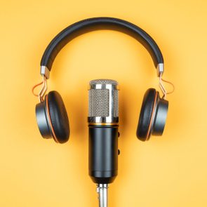 directly above view of headphones and podcast microphone on orange background
