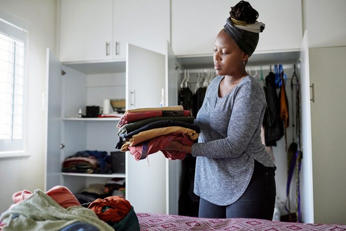 woman organizing the clothes from her bedroom closet at home