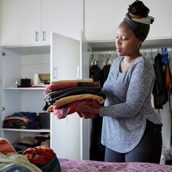 woman organizing the clothes from her bedroom closet at home
