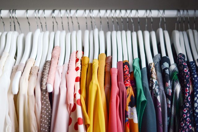 clothing in a closet organized by color from light to dark
