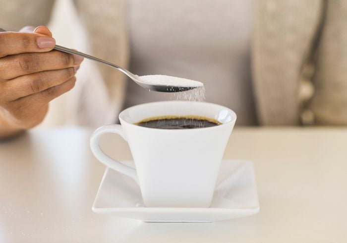 pouring sugar into coffee