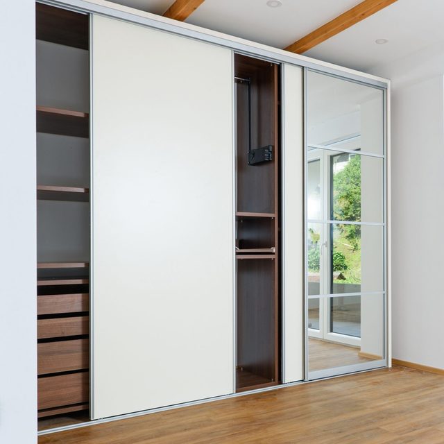 Modern bedroom closet with sliding doors, one panel is a mirror