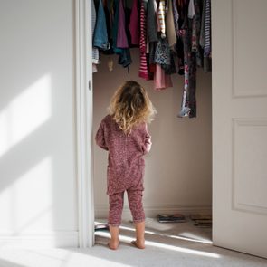 Rear view of girl standing at closet