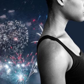 Black and white anonymous portrait of a woman placed in front of colorful night time fireworks over a lake