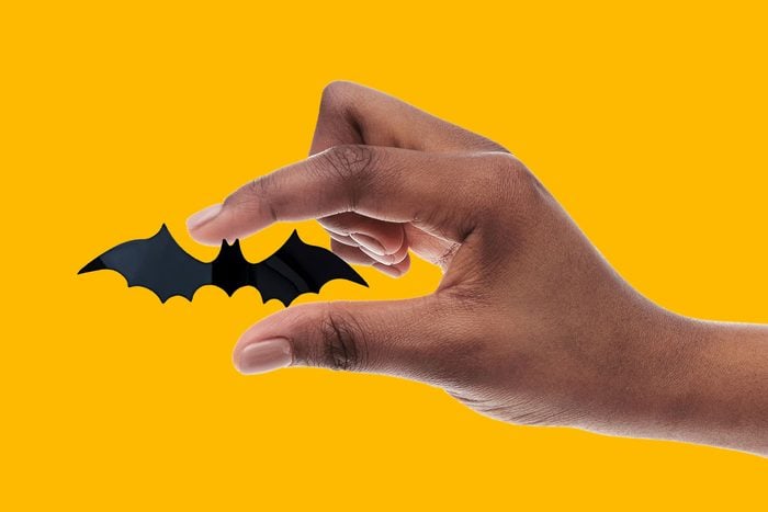 hand holding a representation of a tiny bat between index finger and thumb