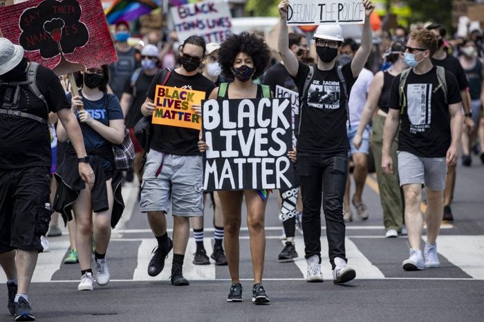 A woman walks among a marching crowd with a "Black Lives Matter" sign in washington, dc