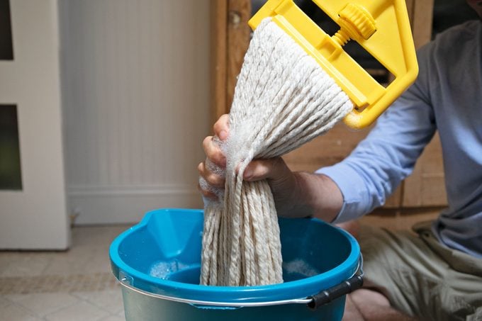 man squeezing water out of mop
