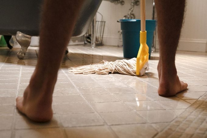 man moving backwards as he mops the bathroom floor