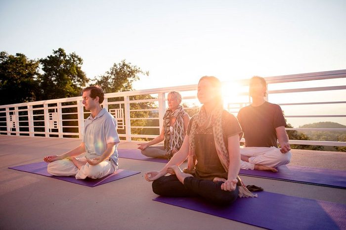 people meditating on yoga mats on a balcony area at Art Of Living Retreat Center, North Carolina