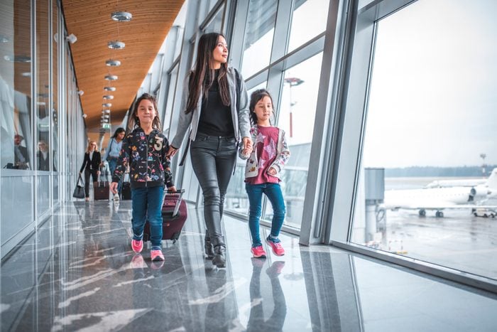 Family with bare faces walking by window at airport terminal