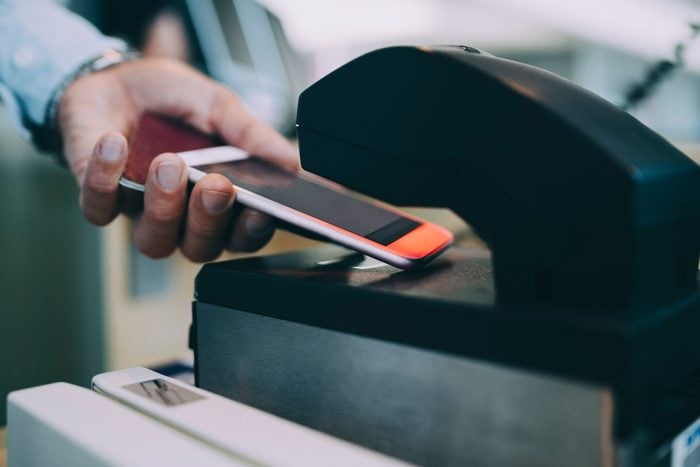 Cropped hands of businessman scanning ticket on smart phone at airport check-in counter