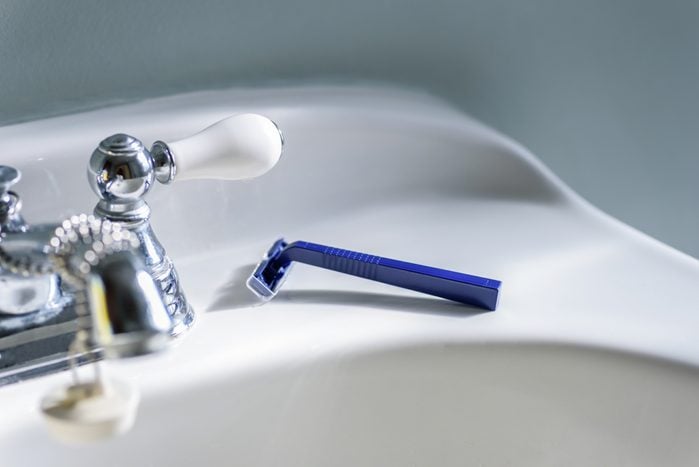Blue razor on white bathroom sink