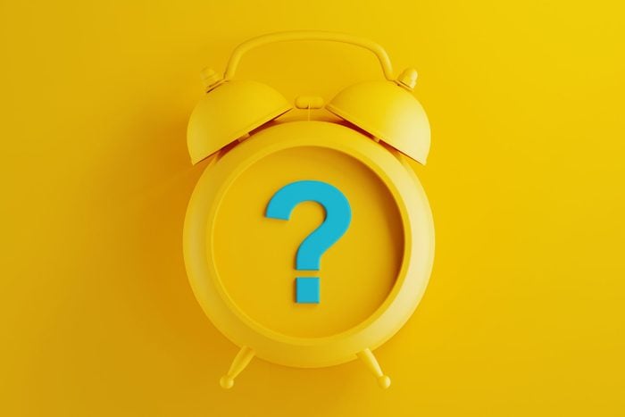 Yellow Alarm Clock with Blue Question Mark on Yellow Background