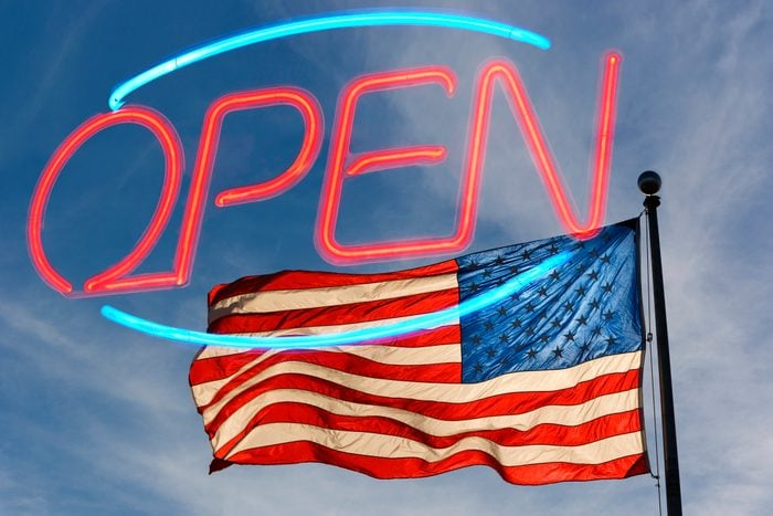 Neon "OPEN" sign with a reflection of the US flag in the background
