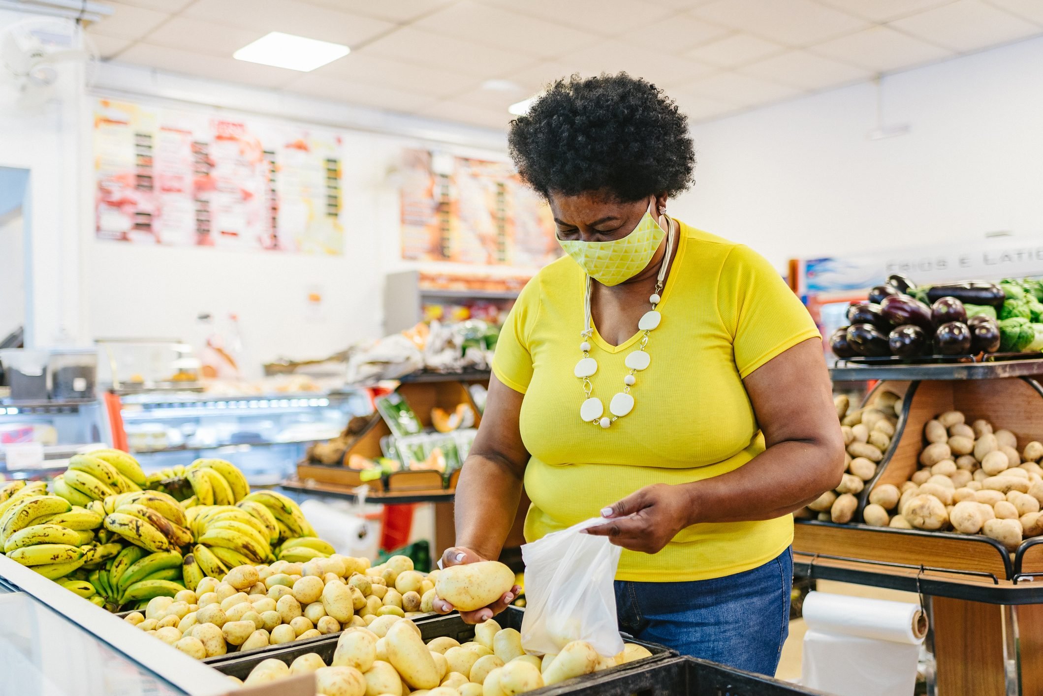 Woman choosing vegetables at the supermarket wearing a face mask