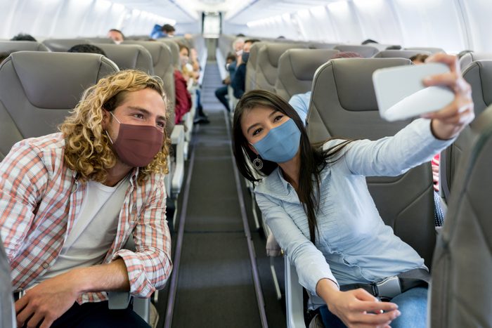 Friends traveling by plane wearing facemasks and taking a selfie