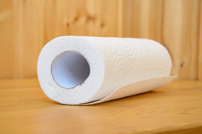 Roll of paper towels on a wooden table against a background of wooden walls.