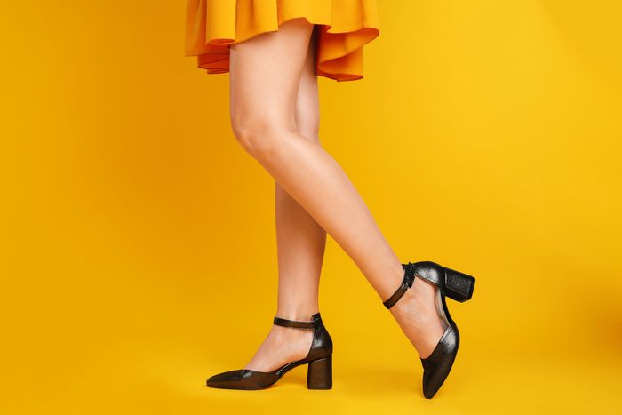 feet in black heels walking on a yellow bacckground