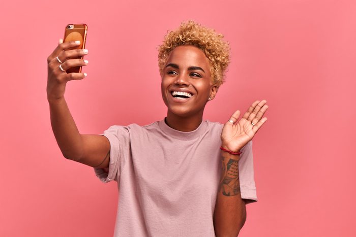 woman taking selfie on a pink background