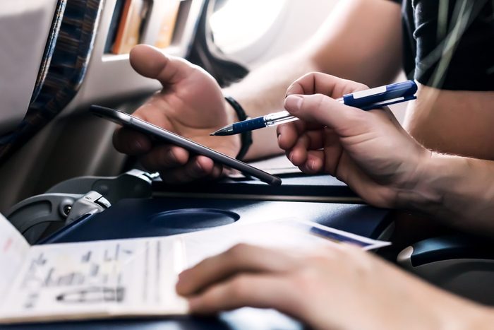 Hands of flight Passengers filling immigration forms in aircraft