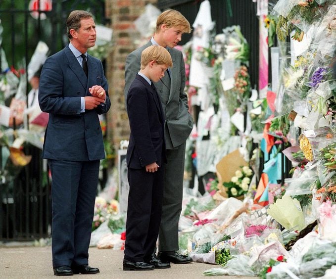The Prince of Wales, Prince William and Prince Harry look at floral tributes to Diana, Princess of Wales outside Kensington Palace on September 5, 1997 in London, England.