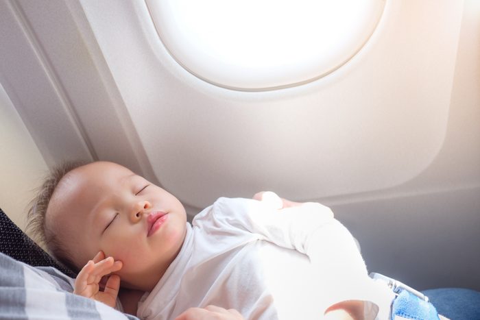 Baby sleeping on parents lap on an airplane