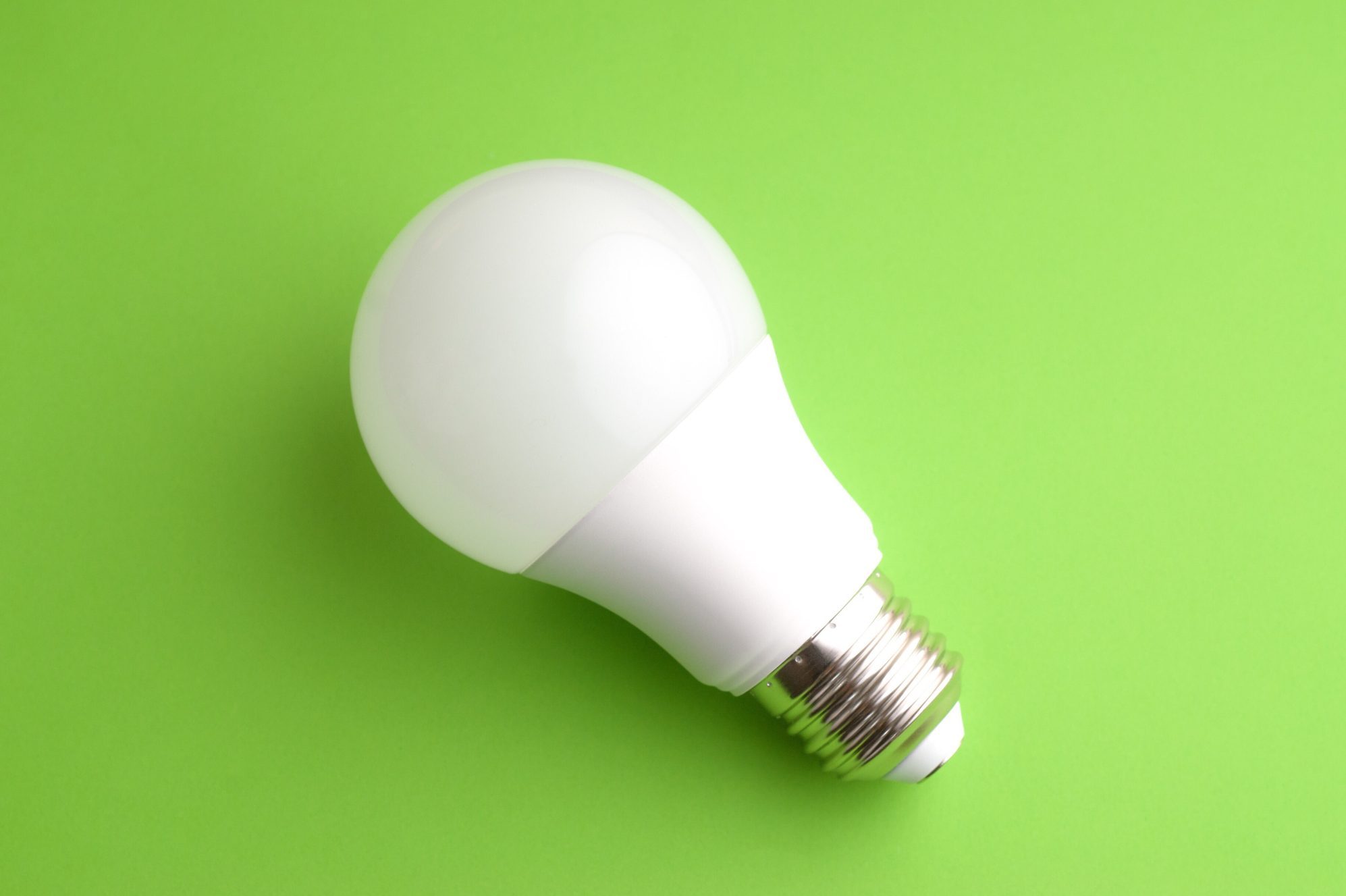 White led light bulb on green background