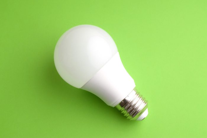 White led light bulb on green background