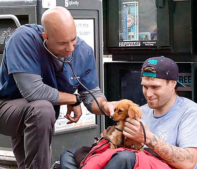 Dr. Stewart using a stethoscope on one of his homeless client's dog
