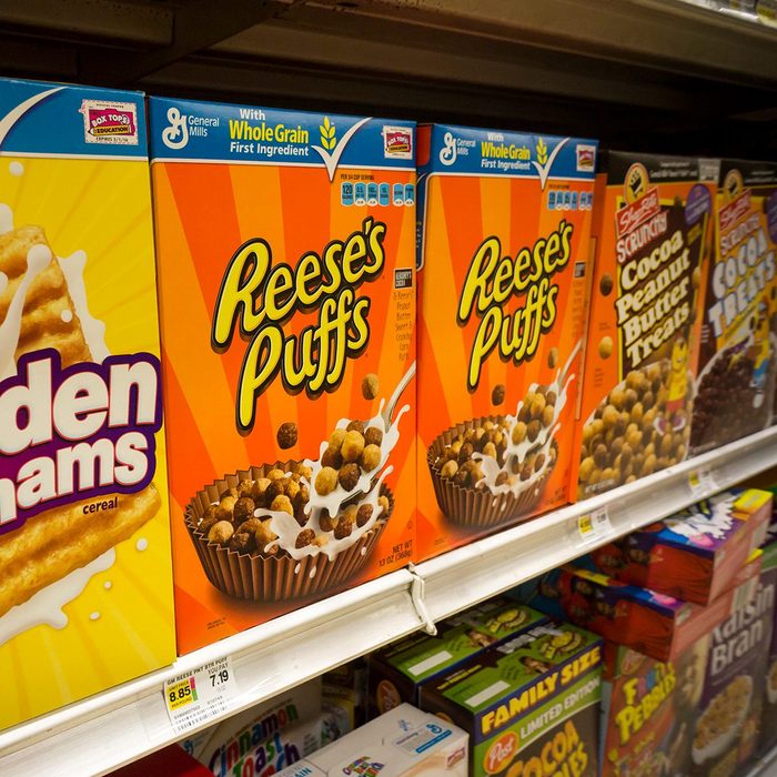 boxes of cereal on a grocery store shelf including Reeses puffs