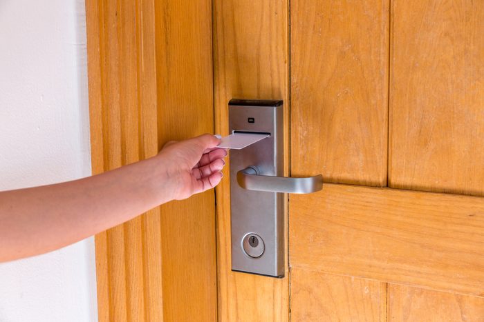 Female hand putting and holding magnetic key card switch in to open hotel room door