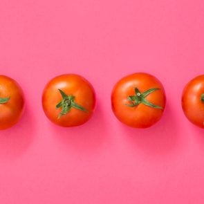 four red tomatos on a pink background