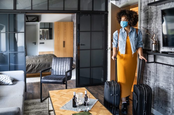 Beautiful afro woman with protective face mask arriving in hotel room