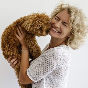 Woman in knitted sweater with her maltipoo poodle.