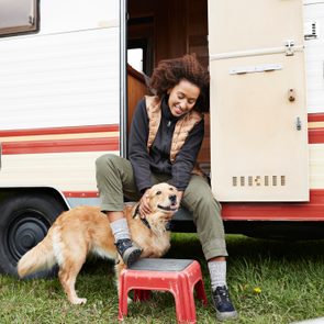 Woman sitting with golden retriever on doorway of camper van