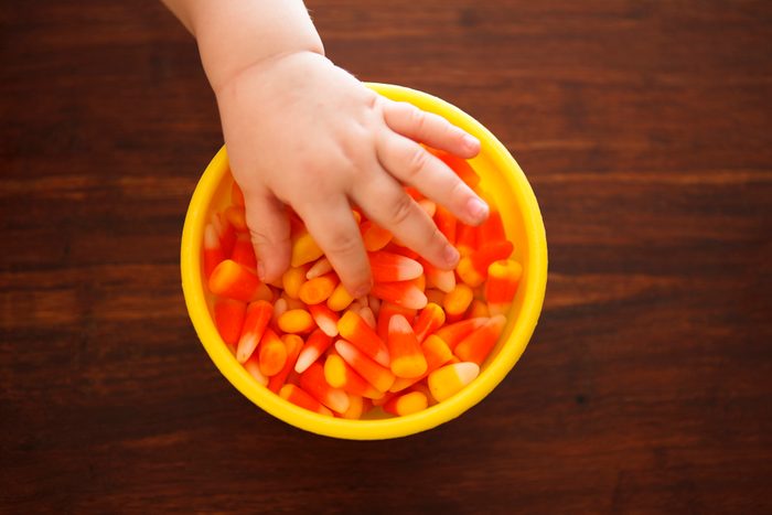 kids hand taking candy corn from a dish on a table