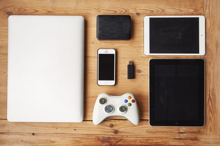 overhead view of laptop, tablets, phone, flash drive, and video game controller on wood background
