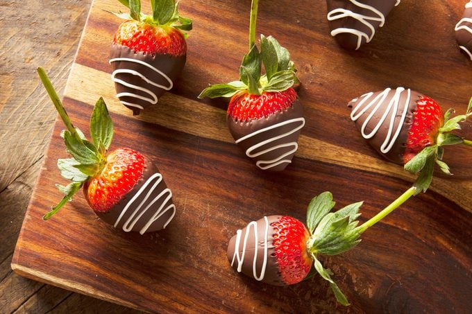 chocolate covered strawberries on a wooden cutting board