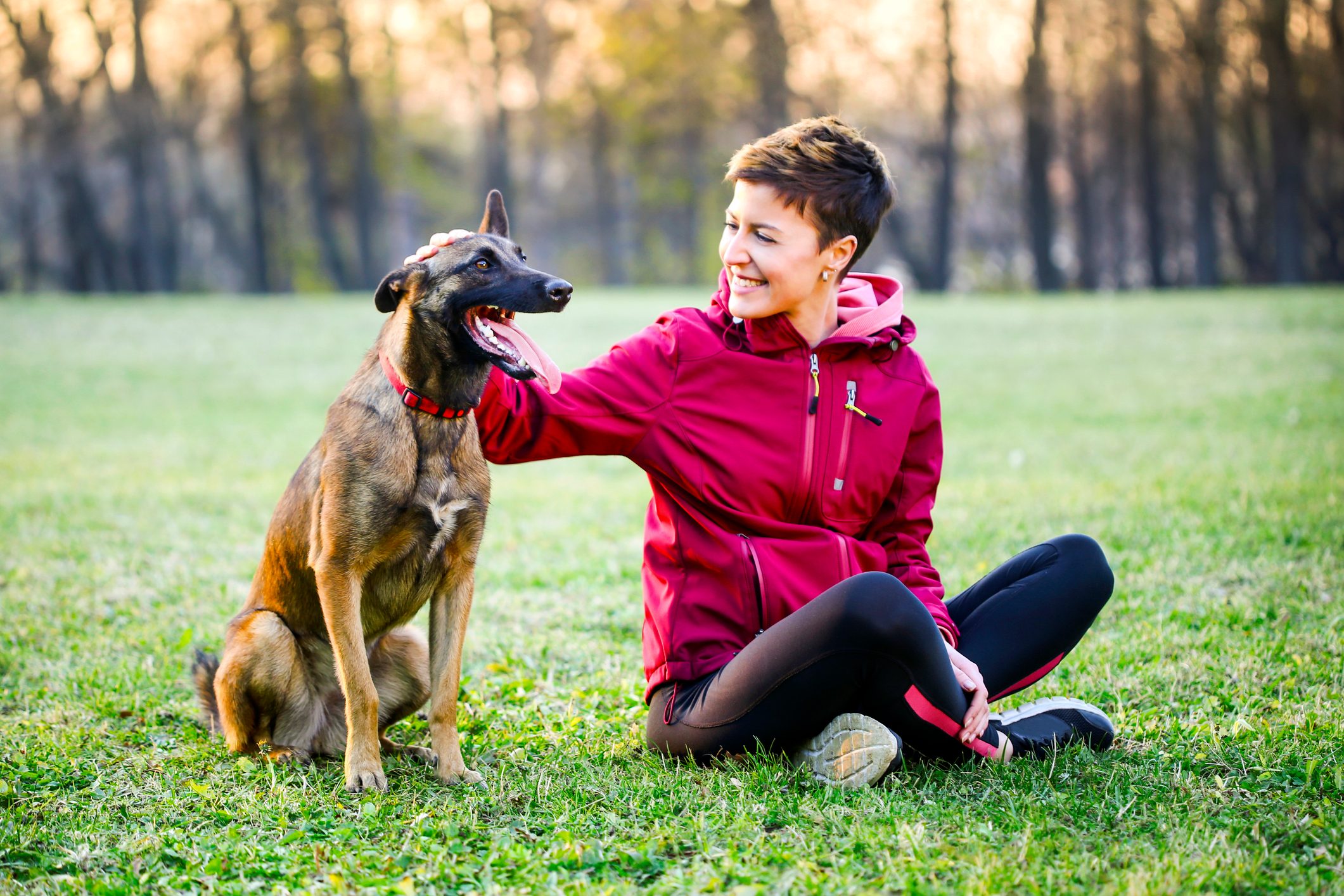 Young woman enjoying time outdoors with her belgian malinois dog pet.