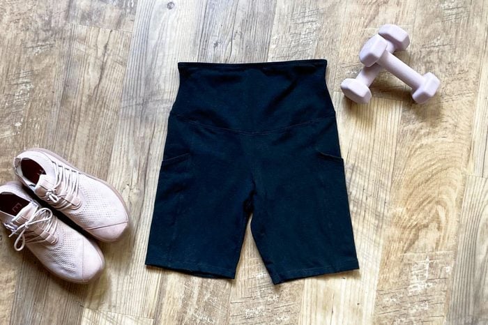 Yummie Bike Shorts in black on wood background with hand weights and sneakers