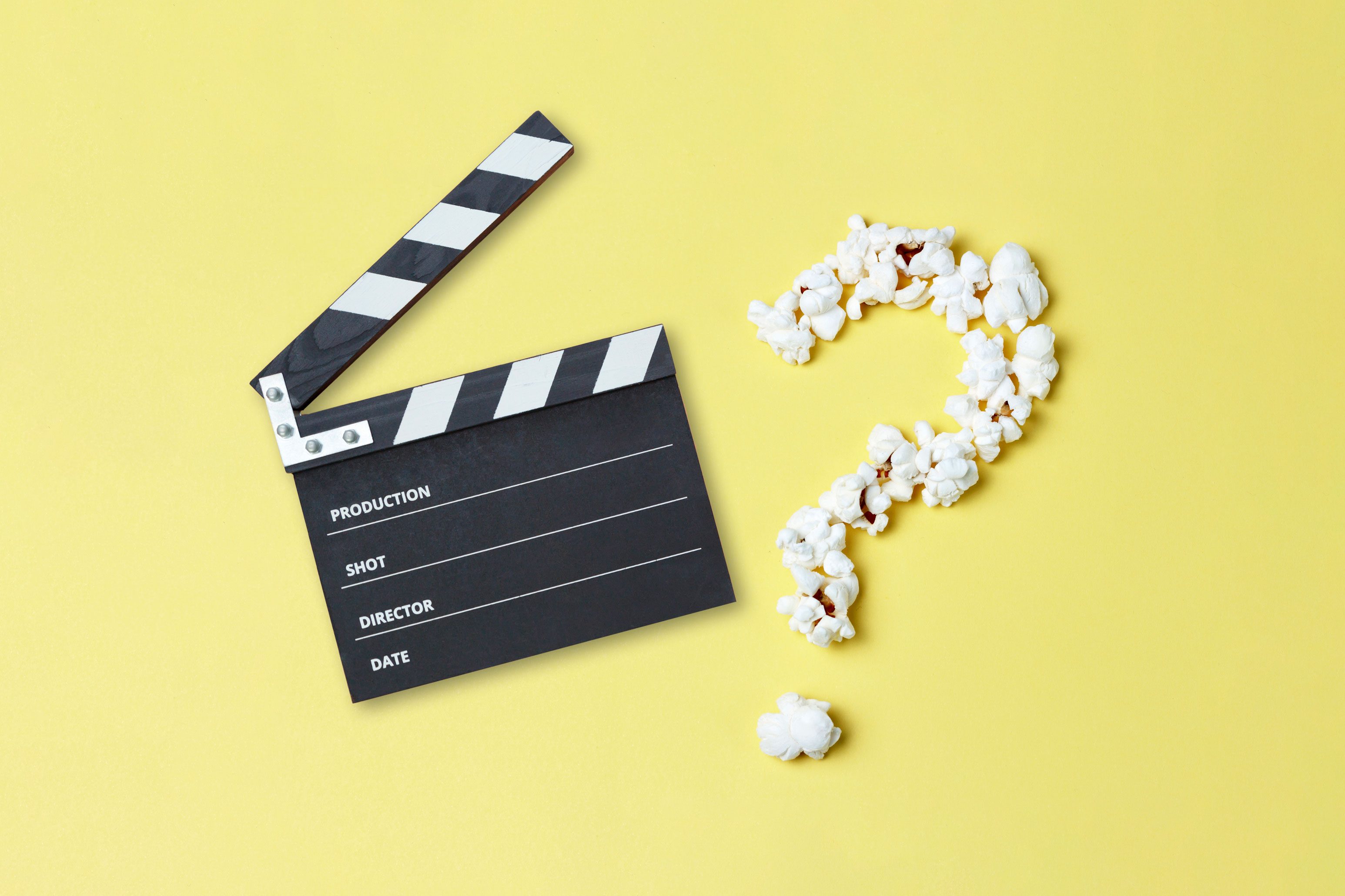 Open Hollywood clapperboard next to popcorn in the shape of a question mark